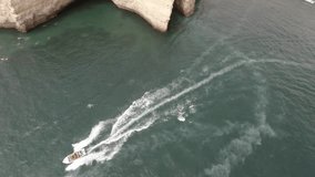 Aerial drone footage revealing a boat heading towards the beaches and caves of Portugal.