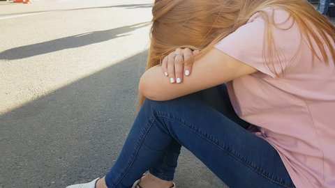 Girl feels sick on street, sitting on pavement, suffering hangover, depression