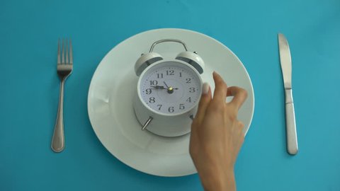 Alarm clock on plate, adhere to diet time, proper nutrition, discipline, closeup