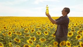 Man farmer hand hold bottle of sunflower oil n the field at sunset. Sunflower oil improves skin health and promote cell regeneration. slow motion video. man farmer agriculture lifestyle plastic bottle