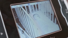 A shot of a baby monitor with a cute newborn baby girl sleeping in her crib