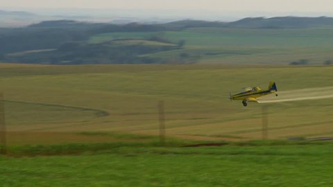 A sprayer plane in low flight disappear in the cornfield