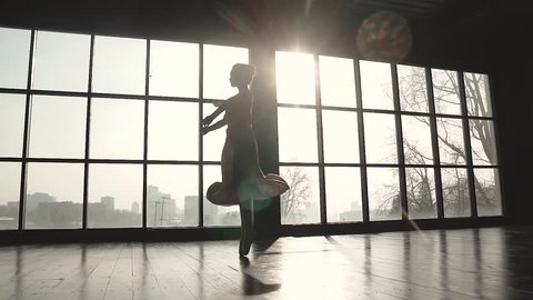 ballerina is spinning in a long fluttering dress. Ballet dancer in pointe shoes on the background of a solar window. slow motion
