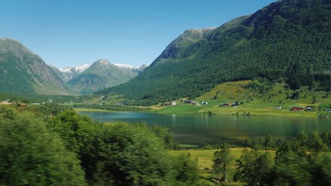 A picturesque Norwegian fjord, on the banks along the water, traditional wooden houses. Idyllic landscape, view from the window of a traveling car