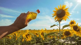 slow motion video. Man lifestyle farmer hand hold bottle of sunflower oil the field at sunset. man farmer agriculture plastic bottle oil sunflower concept. man shows on the production of sunflower oil