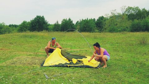 A man and a woman attach the tent arcs to the tent.