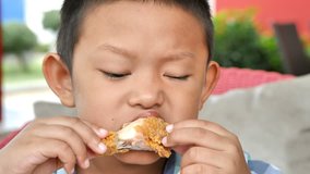 Cute asian boy are happy eating fried chicken leg in restaurant. Video 4k Slow motion