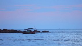 Fisherman in a small wooden fishing boat navigating across the south china sea, under tropical sunset skies high definition stock footage clip.