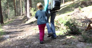 4k video. Four years age blonde girl holding hand to her mother, hiking or walking in forest in the countryside of Guadarrama mountains, Madrid, Spain, Europe
