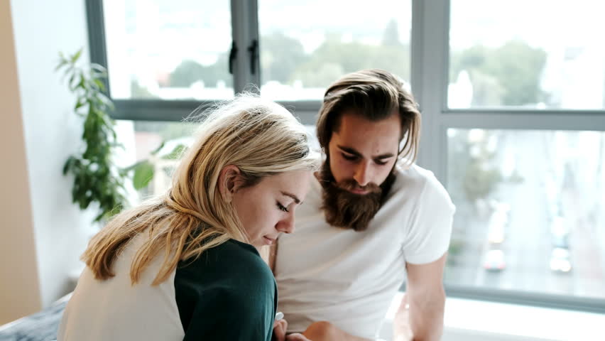 Happy couple using mobile phone on bed at home 4k