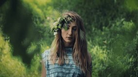Vertical video. Portrait of mystical girl in the woods hold a ritual. She dressed in long dresses with wreath on the head. Witches, esoteric sessions, magic, divination, otherworldly forces
