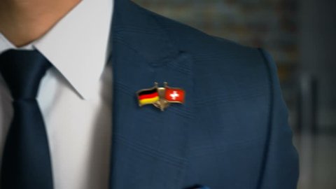 Businessman Walking Towards Camera With Friend Country Flags Pin Germany - Switzerland