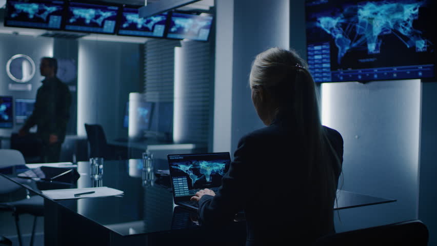 Female Special Agent Works on a Laptop in the Background Special Agent in Charge Talks To a Military Man in the Monitoring Room. Shot on RED EPIC-W 8K Helium Cinema Camera. | Shutterstock HD Video #1015396645