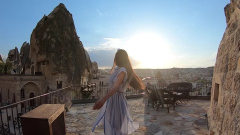 Young beautiful woman walking in front of Cappadocia landscape at sunset. Turkey.
