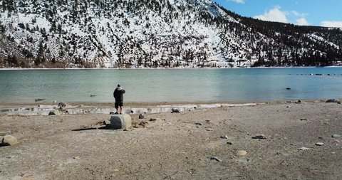 Aerial: Man Standing on Rock and View Across the Water