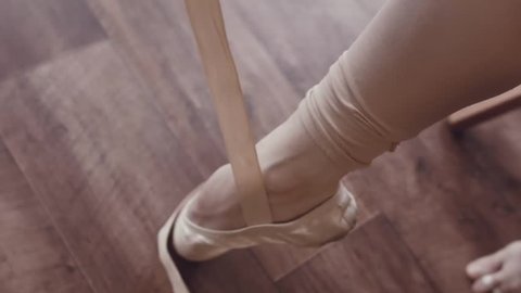 Close-up of ballerina's legs with pointe shoes. Dancer wears ballet slippers. Prepare for the dance. Interior studio in the old style. Natural lighting with haze