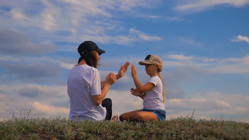 Beautiful young girl playing with her daughter in a summer day in the park . Happy motherhood and a wonderful childhood concept.