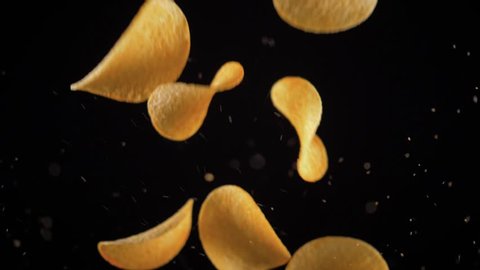 potato chips in free fall on a black background. Slow motion. The view from the side. Pringles