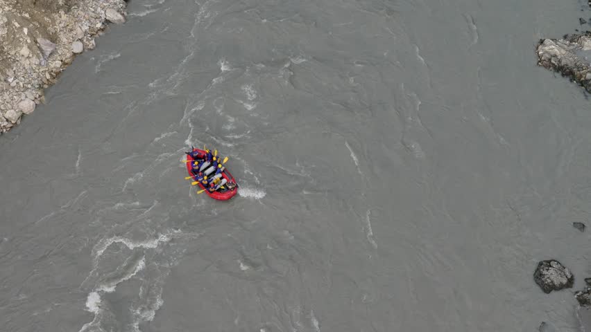 Red raft full of people going down a rapid in the river seen from high above them. Shot in 4K.
