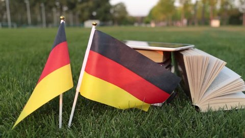 German language and education. Flag of Germany and books on the grass.