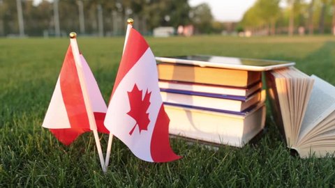 Canadian flag and books on the grass. Education in Canada.