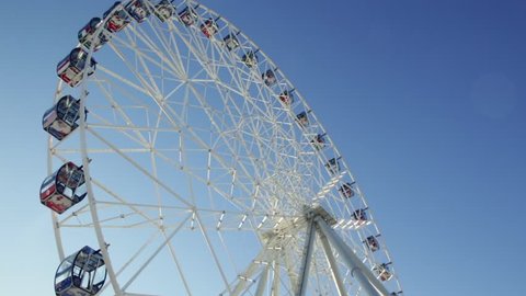 Ferris wheel. Scene. Observation wheel - close up shot. Ferris Wheel Spinning in the Background of a Blue Sky