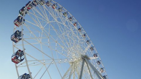 Ferris wheel. Scene. Observation wheel - close up shot. Ferris Wheel Spinning in the Background of a Blue Sky