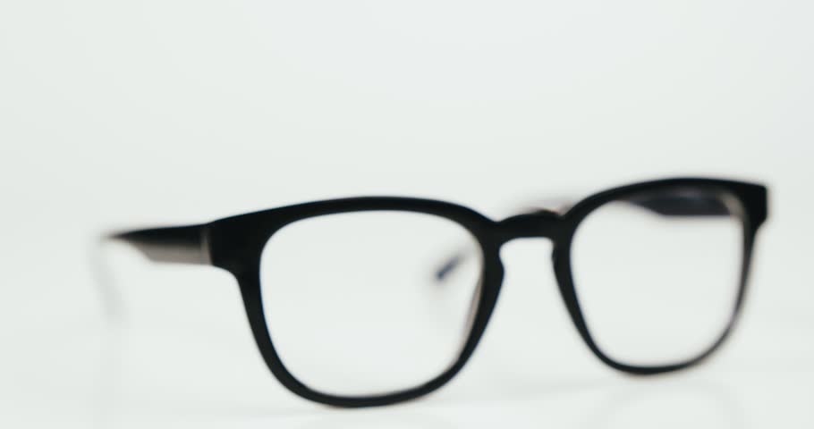 Stylish glasses in black frame isolated on white background and mooving round. Conception of eyesight and vision