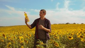 Man farmer hand hold bottle of sunflower oil the field lifestyle at sunset. slow motion video. 