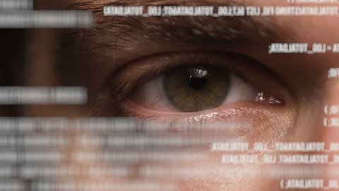 Macro shot of male human eye looking at text on holographic interface or transparent screen analyzed by artificial intelligence.