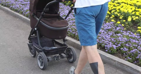 Man walking their baby in a stroller in park