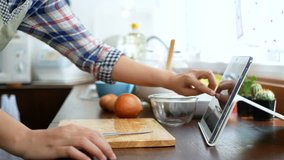 4K. woman use finger slide on tablet screen, slice and peel a onion, prepare ingredients for cooking follow cooking online video clip on website via tablet. cooking content on internet technology