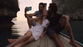 Modern multi ethnic friends taking photo or video with smartphone on long tail boat tour in Asia Thailand. Sunset asian summer holiday travel vacation adventure. Slow motion travel hand held in Asia. 