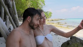 Attractive couple taking photo or video with smartphone on beach in Asia Thailand. Asian summer holiday travel vacation adventure. Slow motion travel hand held.