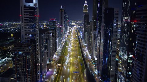 Aerial night illuminated city view Sheikh Zayed road skyline skyscrapers commercial condominiums suburbs vehicle transport highway metro UAE Dubai RED WEAPON