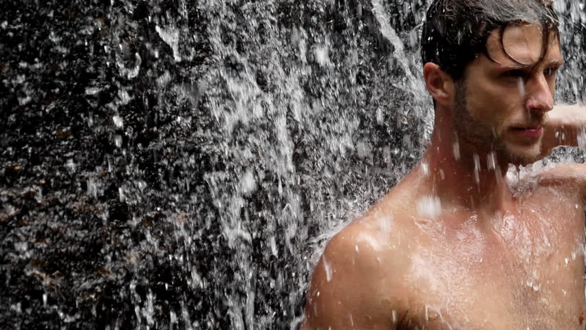 Handsome guy standing under waterfall, Brazil