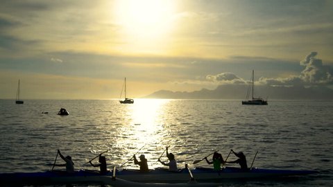 Polynesian Tahitian outrigger manned canoe paddled by females at sunset Moorea Island from Tahiti South Pacific ocean