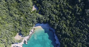 Aerial footage of an isolated secluded beach in the adriatic sea on a sunny summer morning. 4k drone video descending downward.
