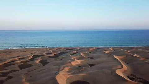 Horizon landscape of beautiful desert with sand dunes, the ocean on the background and blue sky in sunset light. Wonderful peaceful nature landscape, aerial. Gran Canaria