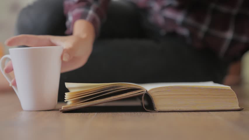 Girl is reading a paper book and drinking coffee, studing dtudent or leisure concept