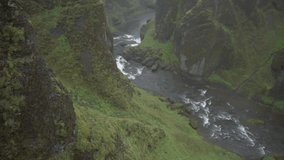 View of man with raised hands up feeling freedom while standing at Fjadrargljufur canyon in Iceland