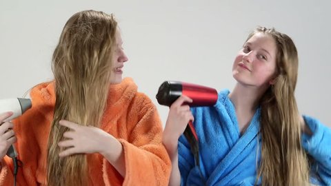 Teenage girls drying long hair after bath with hair dryer