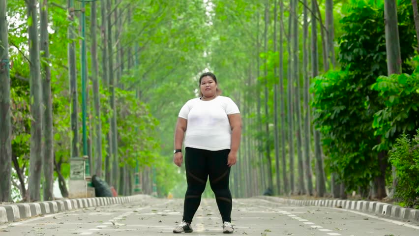 Slow motion of overweight young woman jumping on the street at the park