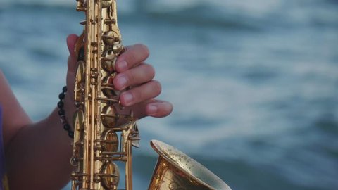Hands of saxophonist playing against the sea