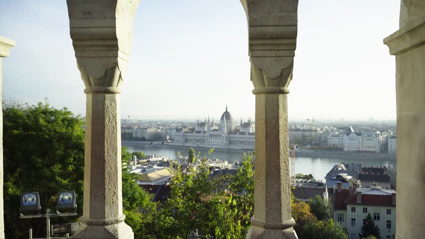 Beautiful woman stands near the columns in the castle on the background of Budapest