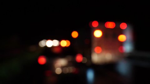 Urban scene with bokeh emergency lights and blurred stationary cars on the road at night