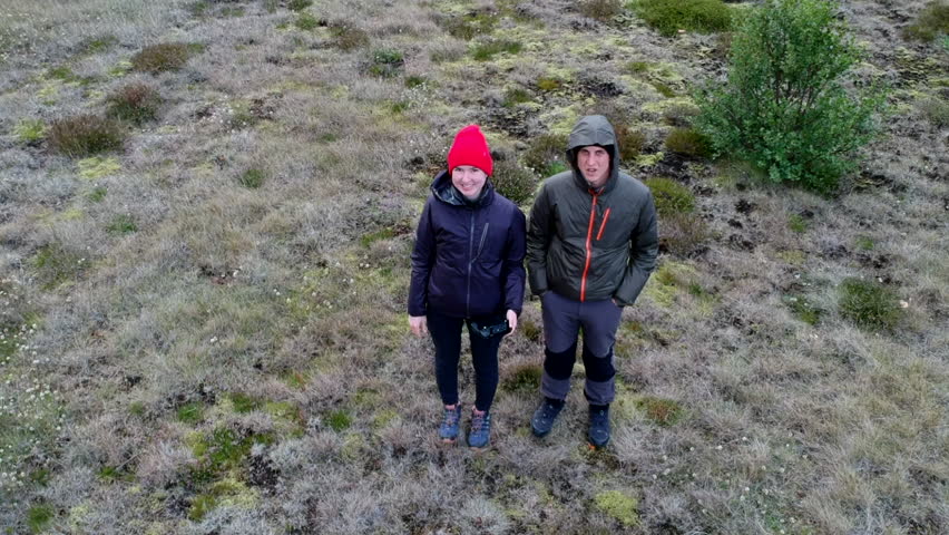 Aerial view of two hikers on Thorsmork mountain ridge trail in Iceland with fast river and mountains on the background