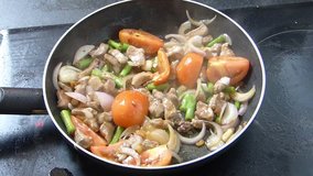 Delicious stir fried pork with vegetables  in hot frying pan on stove top - cooking in slow motion video clip