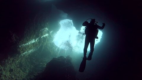 Looking up vertical shaft in reef with silhouette of diver at the Blue Holes in Palau.