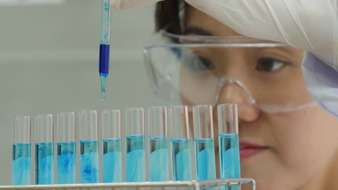Close-up of a scientist with a pipette analyzes a colored liquid to extract the DNA and molecules in the test tubes. 